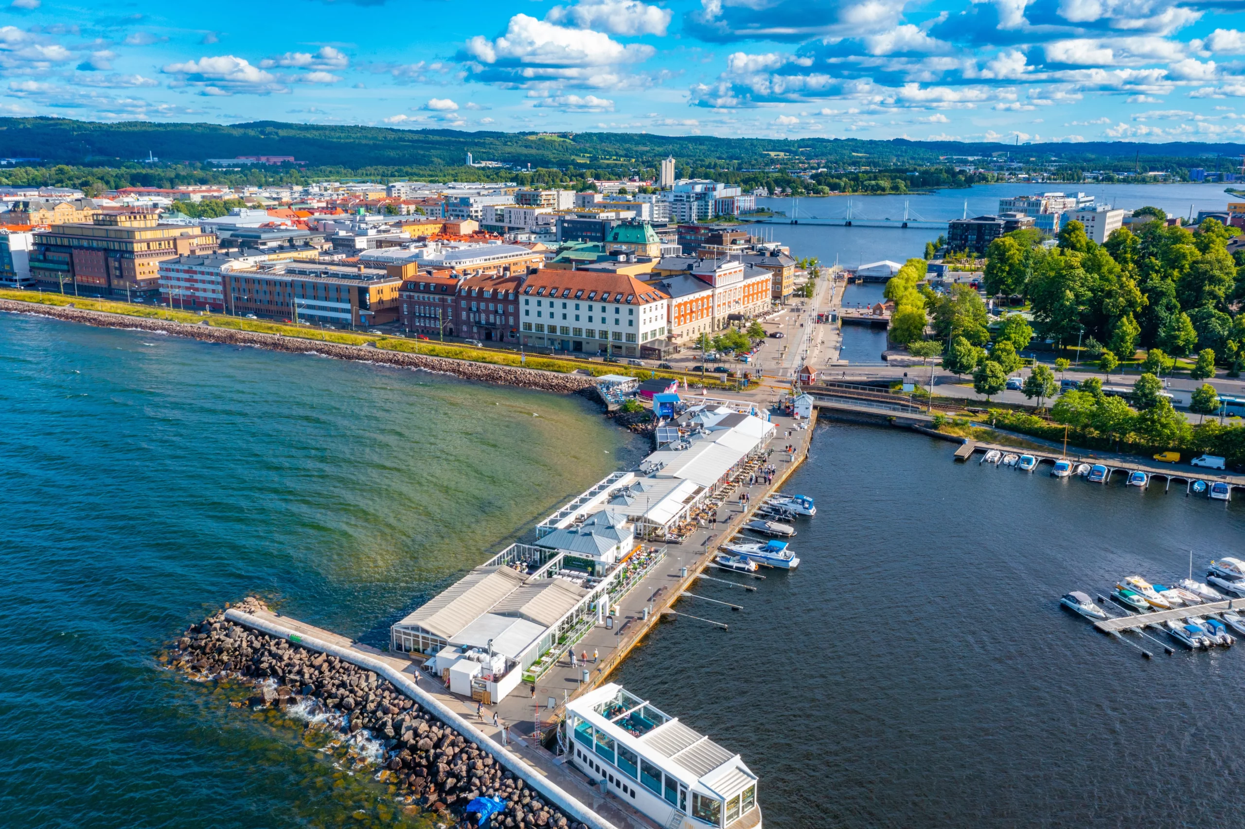 Luftfoto över hamnområde i Växjö med restaurangbrygga, båtar och omkringliggande stadsmiljö.