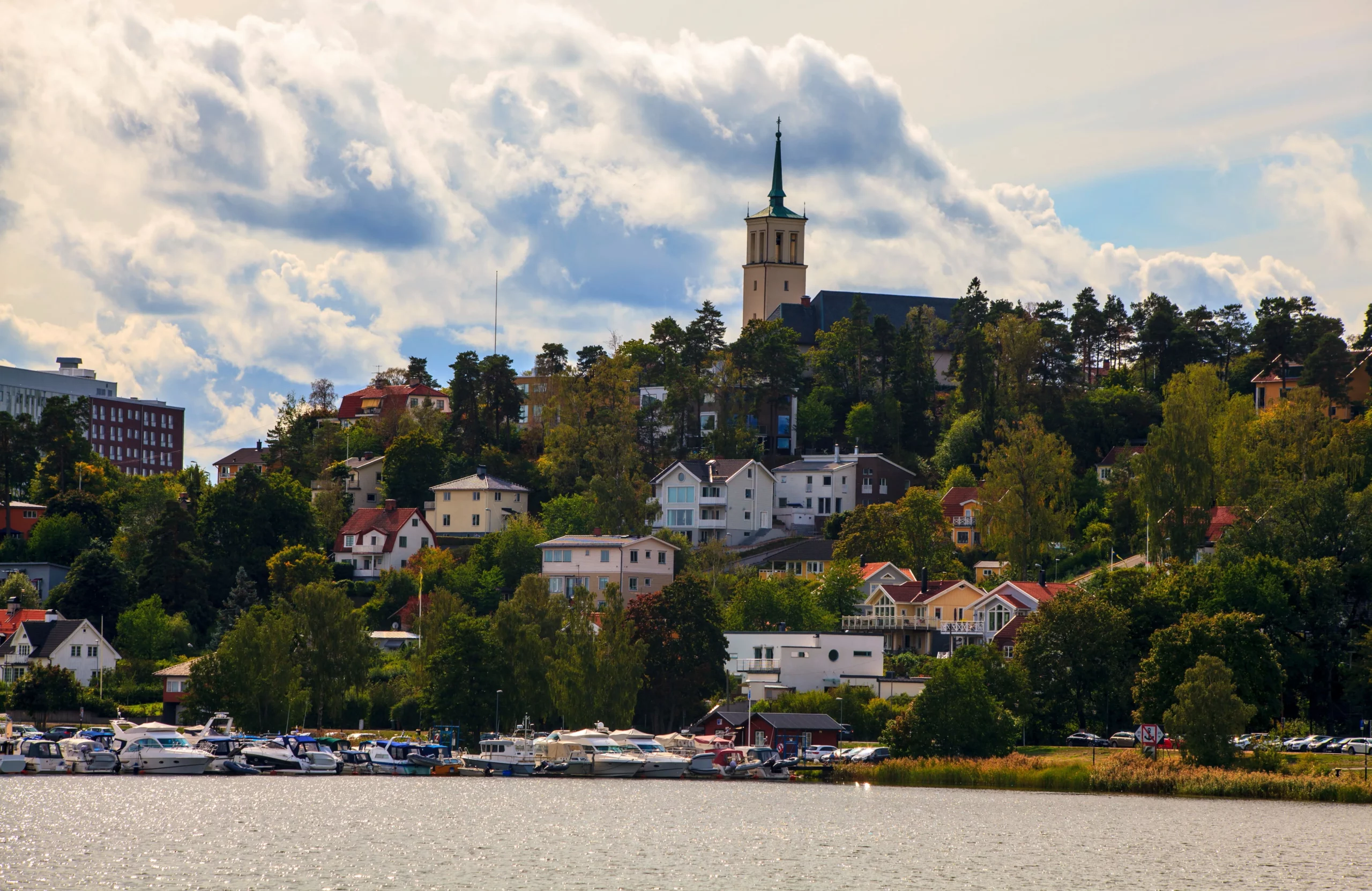 Småbåtshamn och villor vid vattnet i Sollentuna, omgivet av grönska.